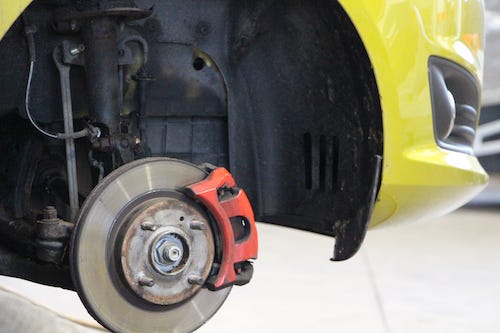 Bremsscheibe und Stoßdämpfer in eingebautem Zustand bei einem gelben Auto